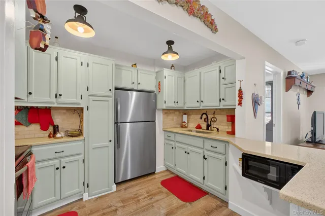 a kitchen with white cabinets and clock on the wall