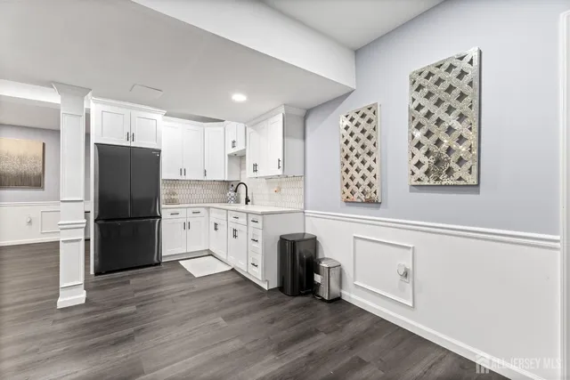 a kitchen with granite countertop a refrigerator a sink a stove a refrigerator and white cabinets