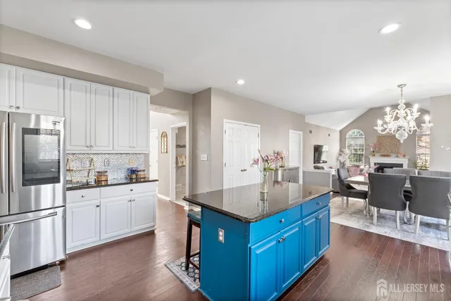 a kitchen with stainless steel appliances granite countertop a refrigerator a sink dishwasher and white cabinets with wooden floor