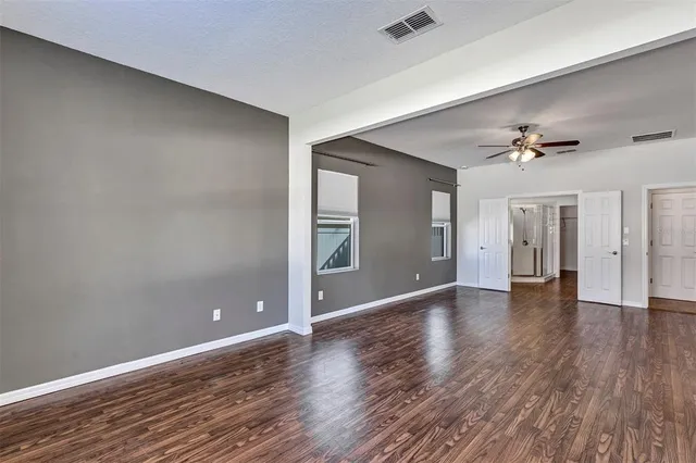 a view of an empty room with window and wooden floor