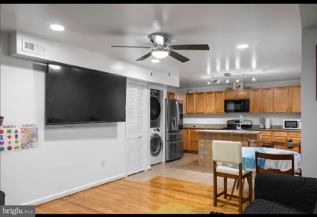 a kitchen with stainless steel appliances granite countertop a refrigerator a stove top oven a sink a dining table and chairs with wooden floor