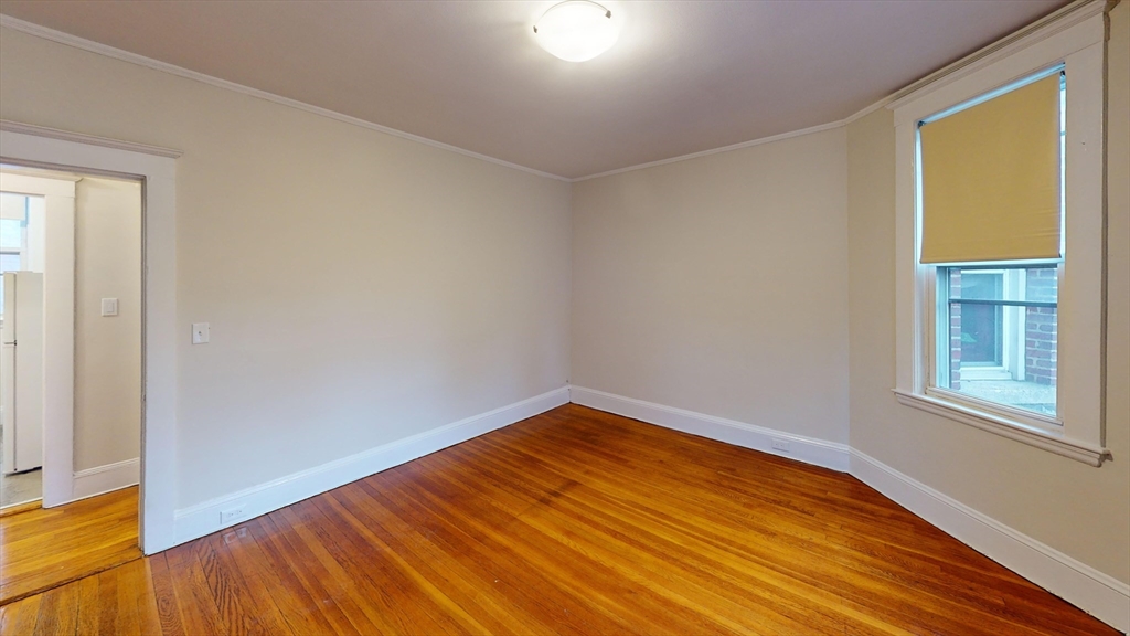 7 Scottfield Road, Unit 8 Boston, MA 02134 - Photo 3 of 6 an empty room with wooden floor and windows
