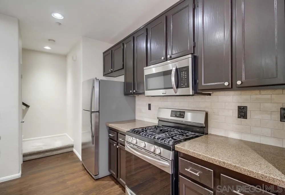 1298 Fools Gold Way, Unit 4 Chula Vista, CA 91913 - Photo 12 of 38 a kitchen with stainless steel appliances granite countertop a stove microwave and refrigerator