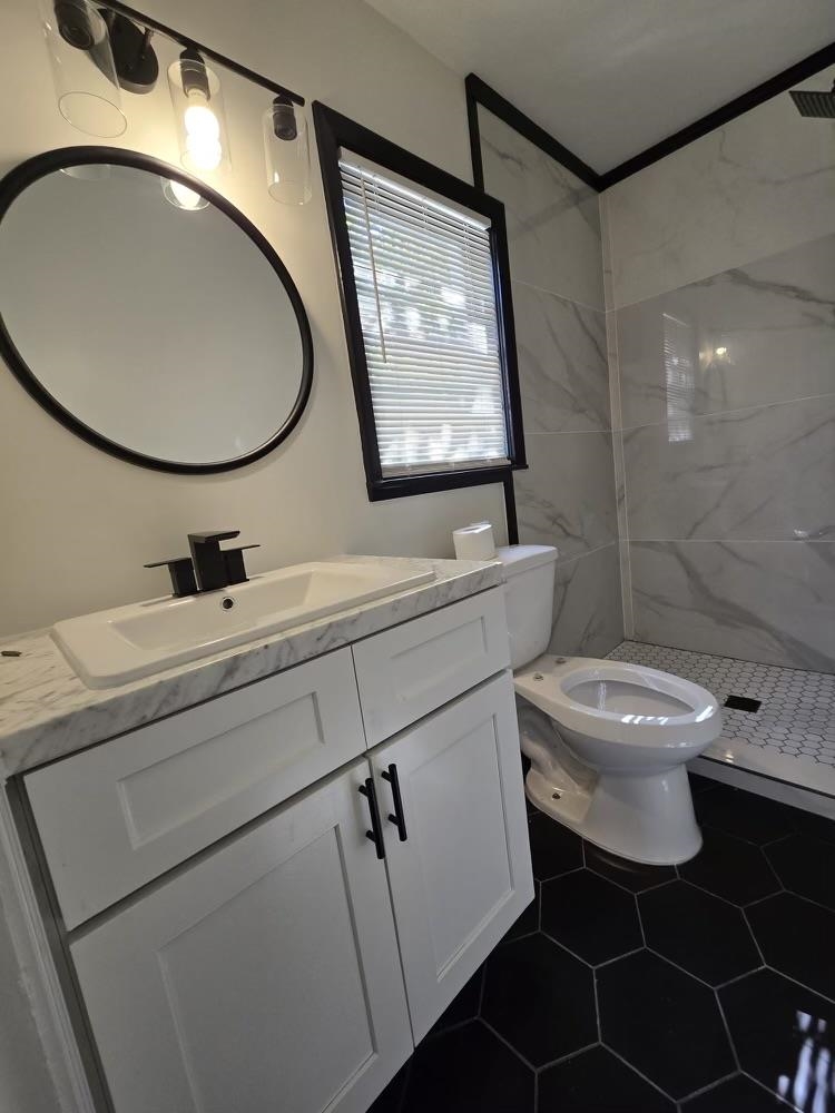 4491 Raleigh Millington Road Memphis, TN 38128 - Photo 15 of 16 Beautifully remodeled bathroom featuring a tile shower, toilet, tile patterned floors and vanity.