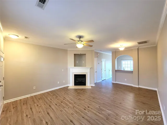an empty room with wooden floor fireplace and windows