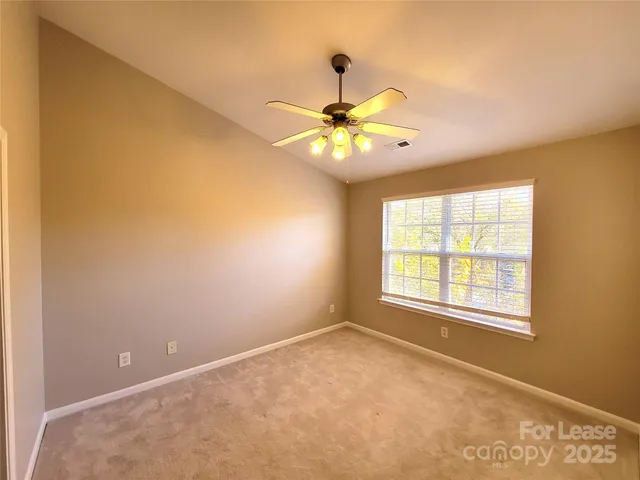 an empty room with a window and a ceiling fan