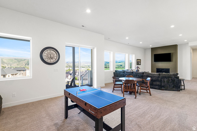 851 Grandview Drive Morgan, UT 84050 - Photo 41 of 68 Open-concept recreation area featuring multiple large windows, sliding glass door access to an outdoor space, recessed lighting, and a textured accent wall with a fireplace