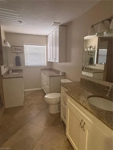 a bathroom with a granite countertop toilet sink and mirror