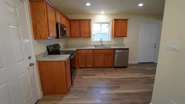 a kitchen with stainless steel appliances granite countertop wooden cabinets a stove a sink and a refrigerator