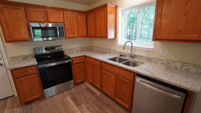 a kitchen with granite countertop wooden cabinets stainless steel appliances a window and a sink