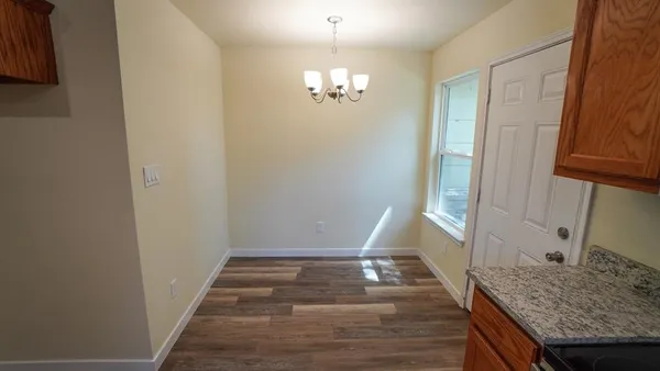 an empty room with chandelier fan and windows