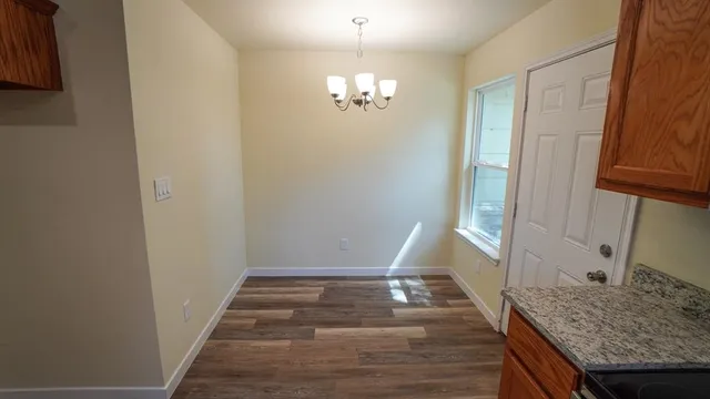 an empty room with chandelier fan and windows
