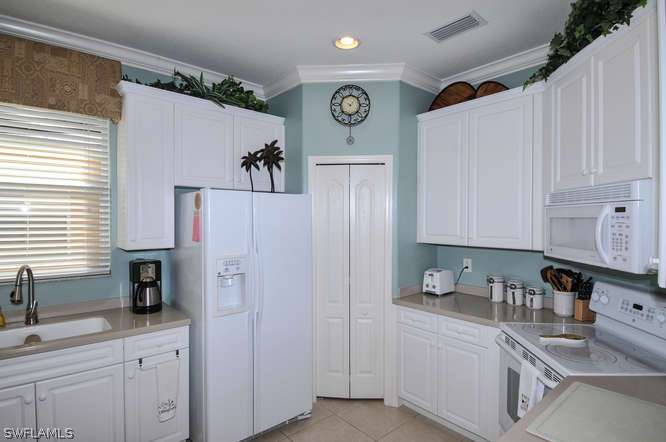4688 Fairloop Lehigh Acres, FL 33973 - Photo 4 of 24 a kitchen with stainless steel appliances a refrigerator sink and cabinets