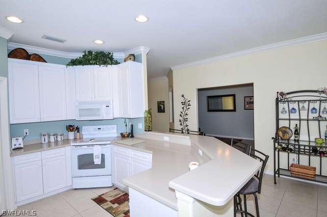 4688 Fairloop Lehigh Acres, FL 33973 - Photo 5 of 24 a kitchen with granite countertop a table chairs sink and cabinets