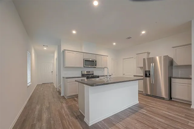 a kitchen with stainless steel appliances granite countertop a sink a stove a refrigerator and a oven