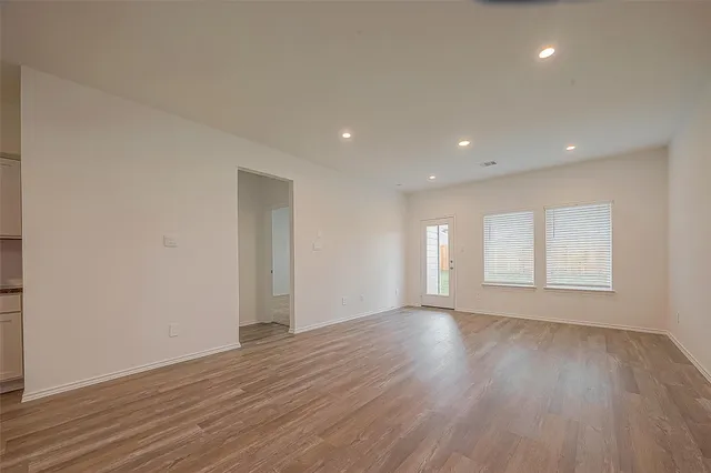 a view of an empty room with wooden floor and window