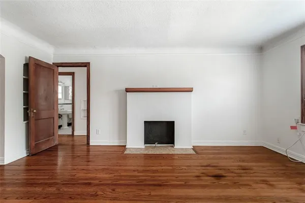 a view of empty room with wooden floor and fireplace