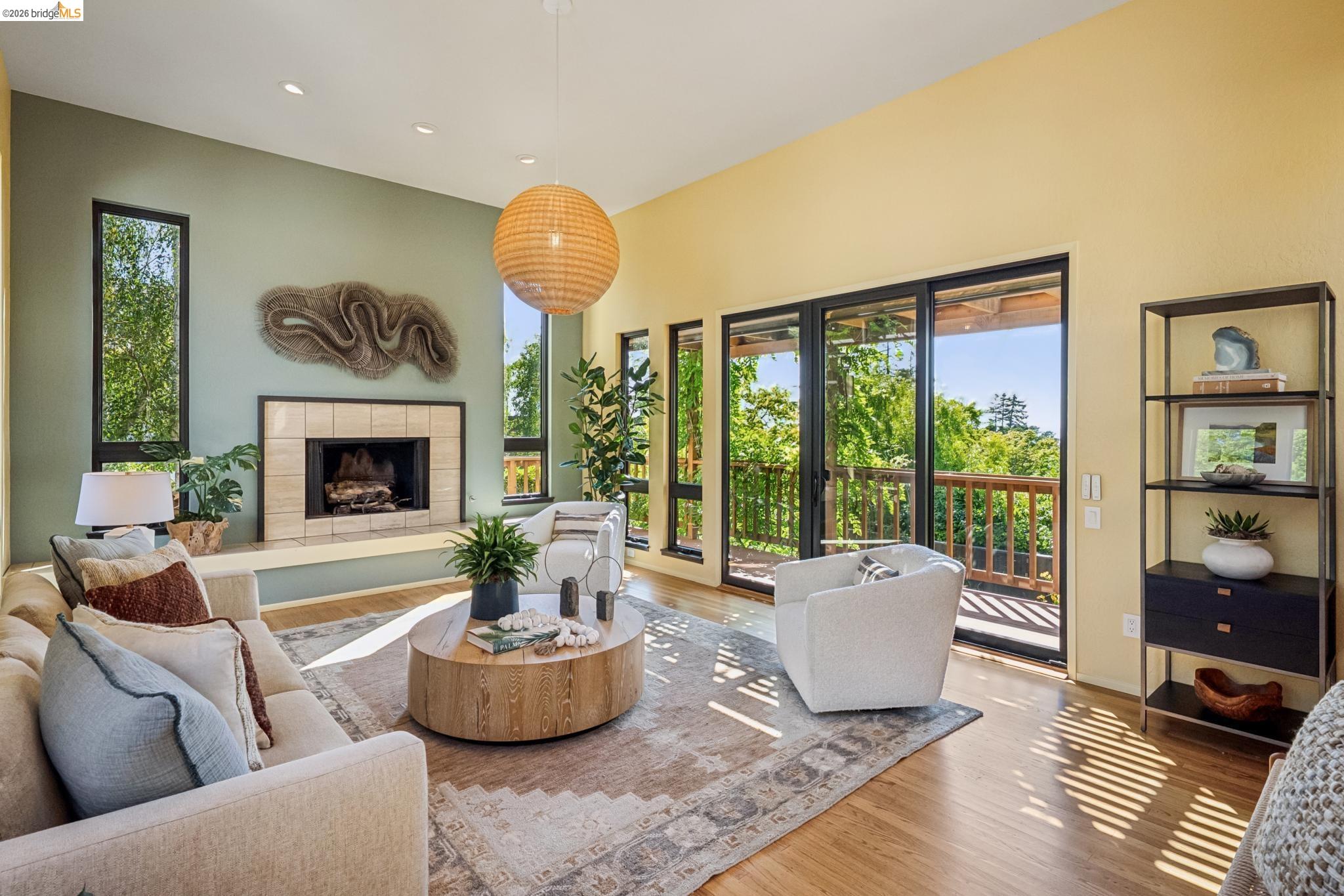 576 Vistamont Avenue Berkeley, CA 94708 - Photo 18 of 33 Spacious living area featuring a fireplace with a tile surround and hearth, wood-finish flooring, high ceilings, large windows, and sliding glass doors opening to a balcony