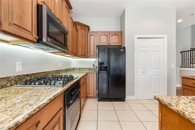 a kitchen with stainless steel appliances granite countertop a refrigerator and a stove top oven