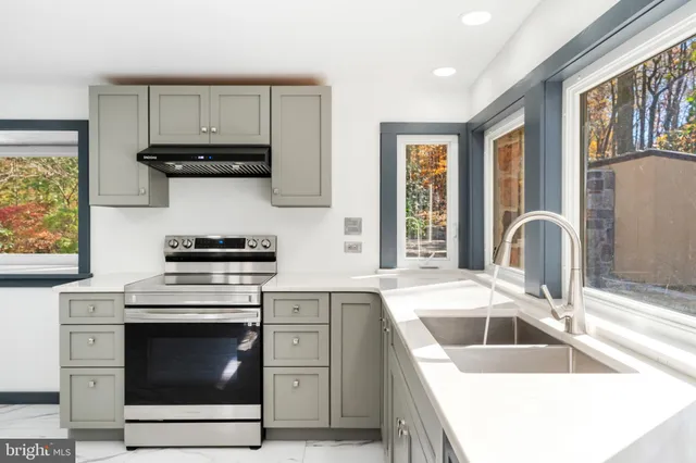 a view of kitchen with stainless steel appliances granite countertop a stove a microwave and a refrigerator