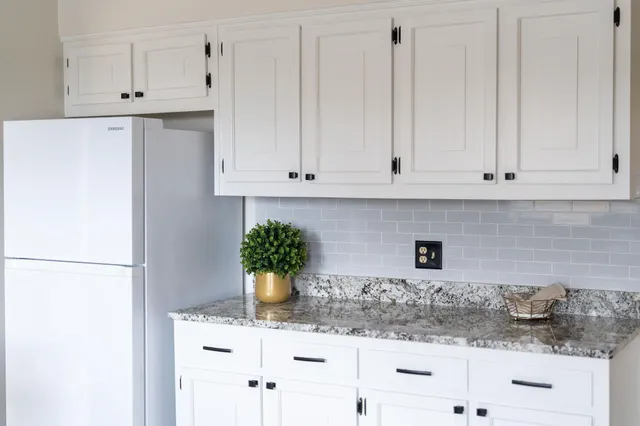 a kitchen with stainless steel appliances granite countertop white refrigerator stove and white cabinets