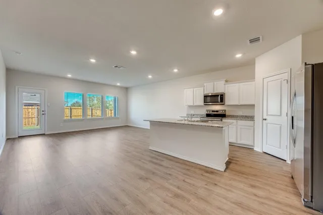 a view of kitchen with granite countertop refrigerator oven a stove and a wooden floors