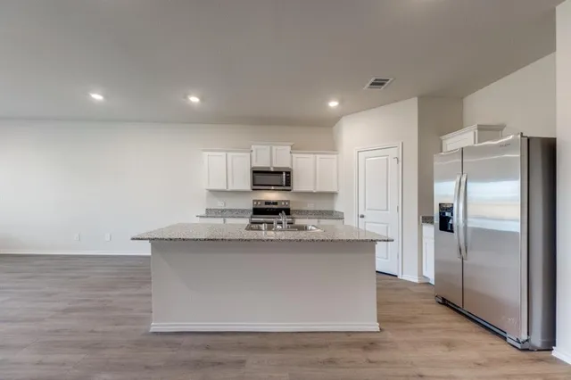 a kitchen with stainless steel appliances granite countertop a stove top oven a refrigerator and a sink