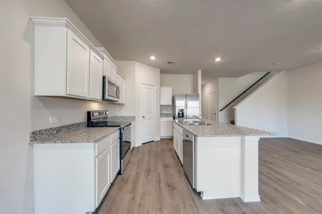 a kitchen with a sink a counter top space stainless steel appliances and cabinets