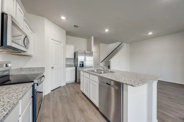 a kitchen with stainless steel appliances granite countertop hardwood floor sink stove and refrigerator