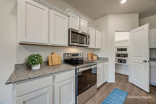 a kitchen with granite countertop a sink stainless steel appliances and white cabinets