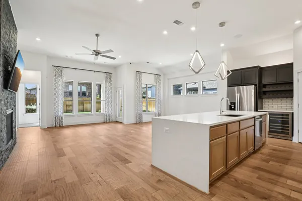 a large kitchen with stainless steel appliances granite countertop a large center island a stove a refrigerator cabinets and wooden floor
