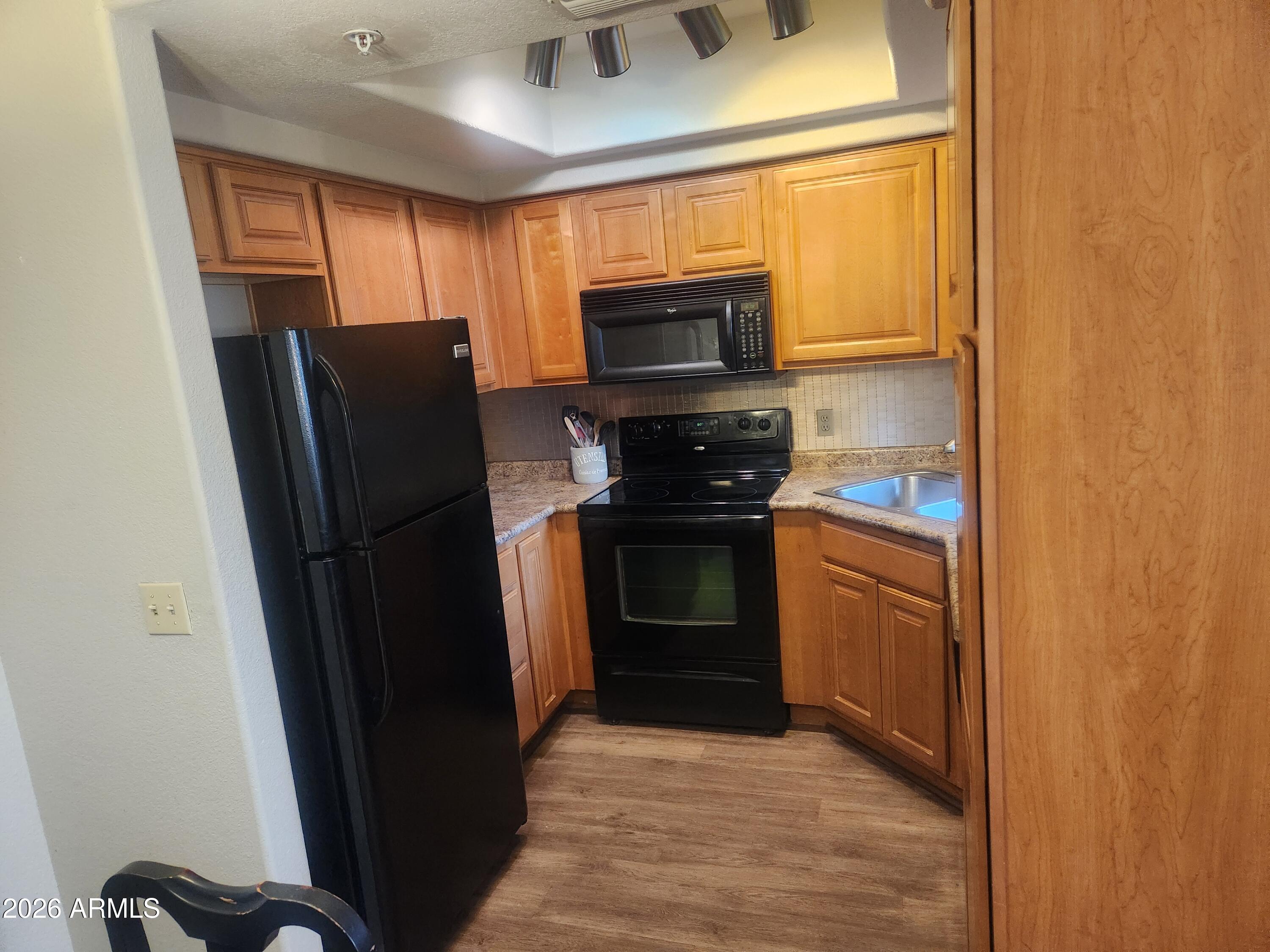 1825 West Ray Road, Unit 2044 Chandler, AZ 85224 - Photo 6 of 14 a kitchen with stainless steel appliances granite countertop a refrigerator a stove a sink and dishwasher with wooden floor