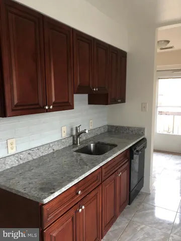 a kitchen with granite countertop wooden cabinets a sink and dishwasher
