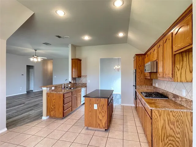 a kitchen with stainless steel appliances kitchen island granite countertop a stove and a sink
