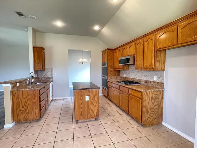 a kitchen with stainless steel appliances granite countertop a stove a sink and a microwave
