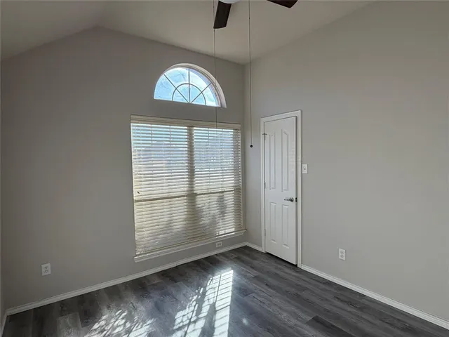 an empty room with wooden floor cabinet and windows