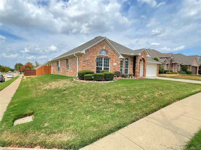 a view of a house next to a big yard and large trees