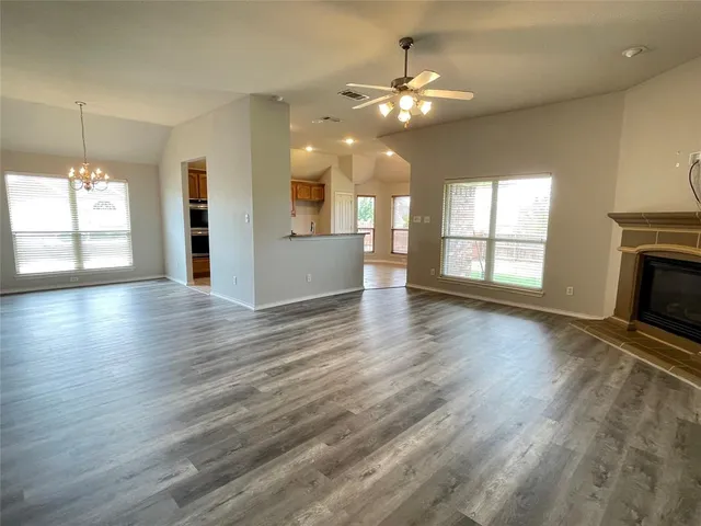 an empty room with wooden floor fireplace and windows