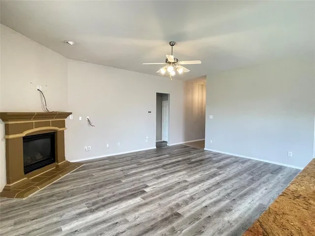 a view of an empty room with wooden floor and fireplace