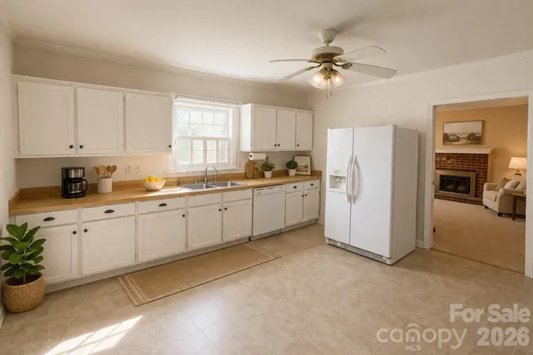 a kitchen with a refrigerator a sink and dishwasher a stove top oven with white cabinets