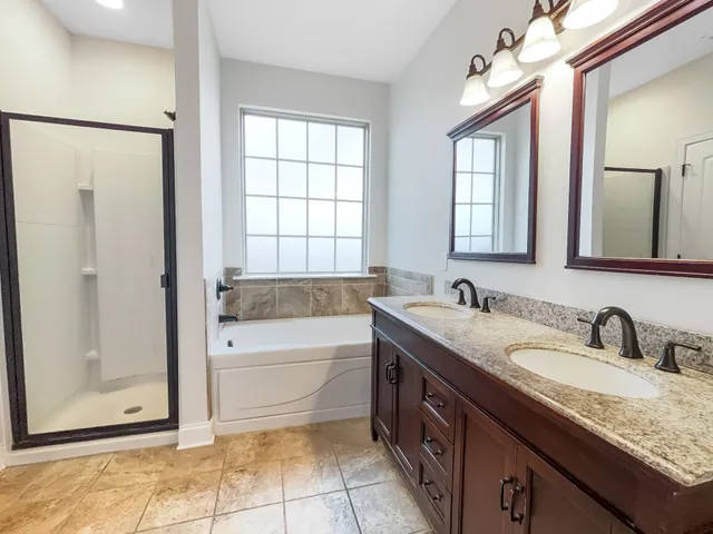 a spacious bathroom with a granite countertop tub sink shower and mirror