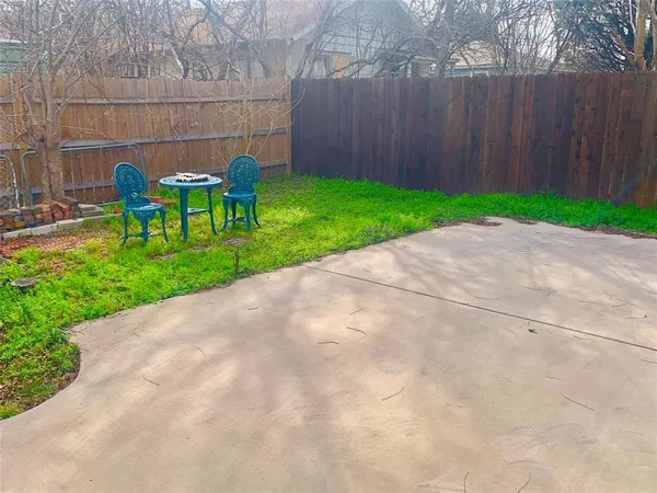 a view of backyard with table and chairs and wooden fence