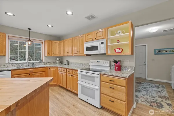 a kitchen with granite countertop a sink cabinets stainless steel appliances and a window