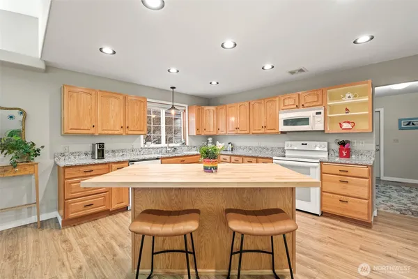 a kitchen with stainless steel appliances kitchen island wooden floor and white cabinets