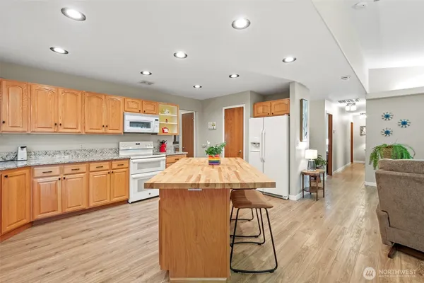 a kitchen with stainless steel appliances kitchen island granite countertop wooden floors and white cabinets