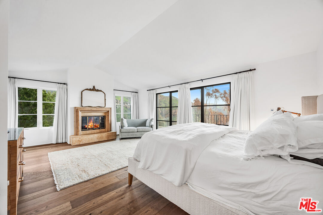 2382 Live Oak Meadows Road Malibu, CA 90265 - Photo 11 of 20 a large white bed in a bedroom next to a window with a fireplace