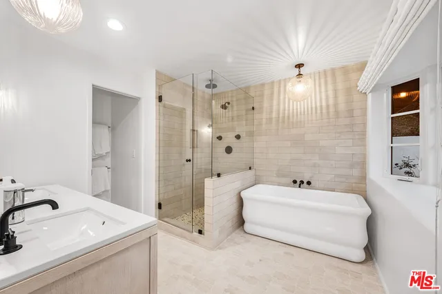 a bathroom with a tub a sink and a large mirror