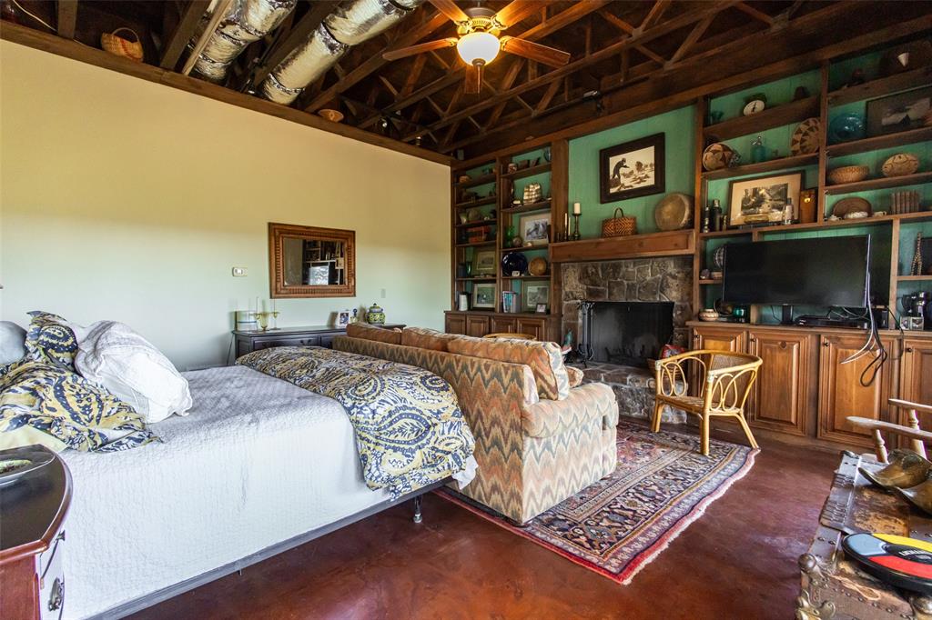 1775 Sunset Mountain Road Lipan, TX 76462 - Photo 14 of 34 a spacious bedroom with a bed a couch and a flat tv screen on the dresser