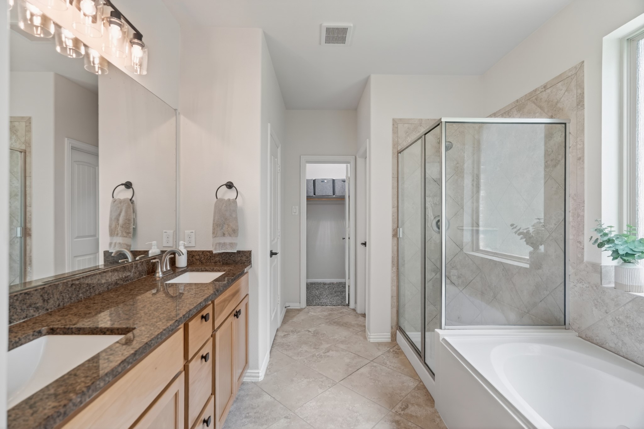 79 West Jagged Ridge Circle Spring, TX 77389 - Photo 24 of 50 The primary en-suite bathroom features a long dual-sink vanity topped with granite countertops, a large mirror, and warm wood-tone cabinetry. This spacious layout offers plenty of room to get ready in the morning without feeling rushed.