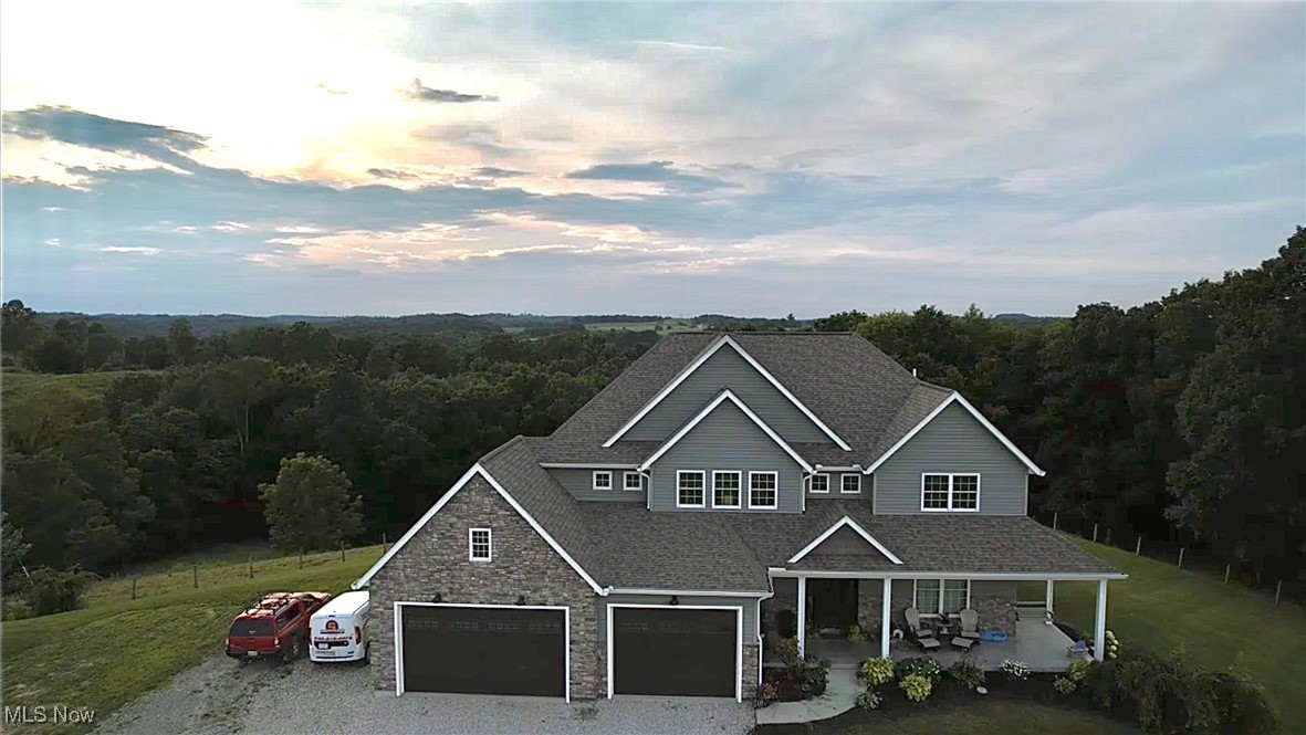 49402 Patton Road Jerusalem, OH 43747 - Photo 1 of 28 View of front of house with a forest view, covered porch, stone siding, and a shingled roof